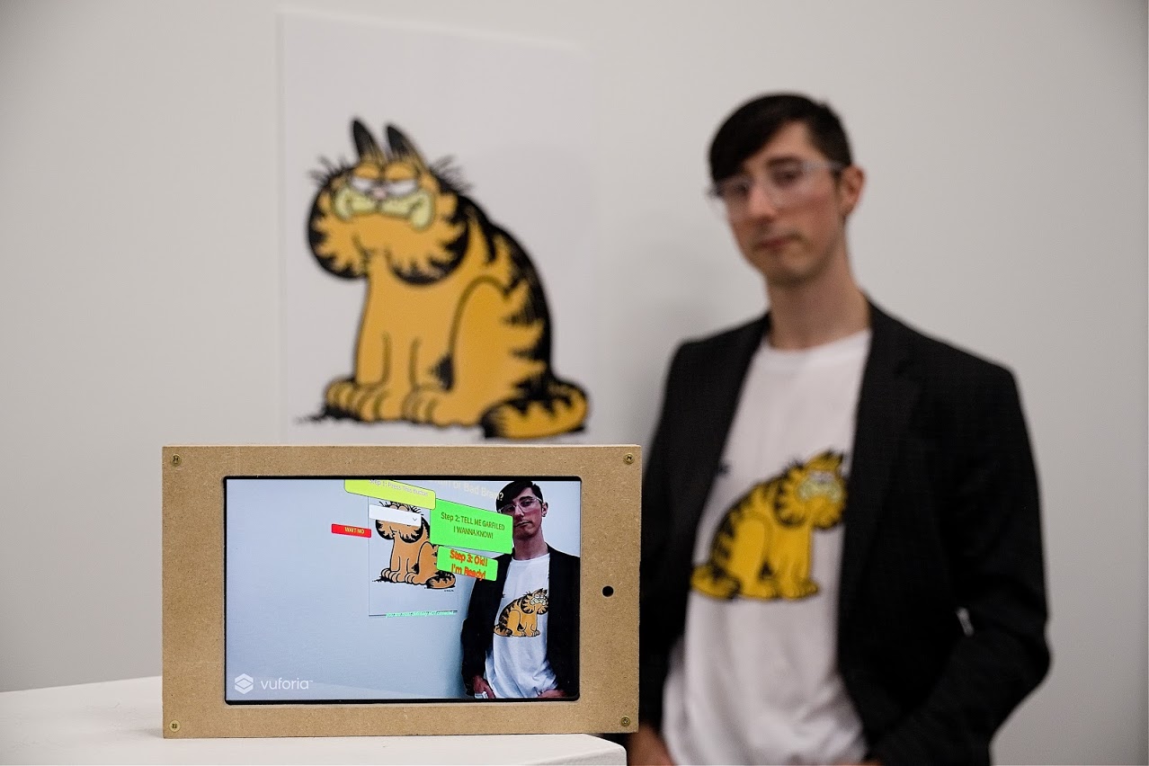 A tablet displaying intentionally ugly UI in front of a person in a Garfield shirt